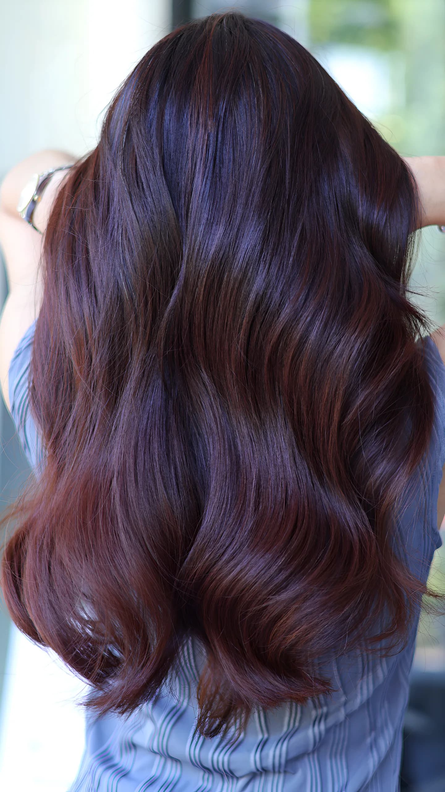 Long glossy hair coloured deep burgundy, seen from behind
